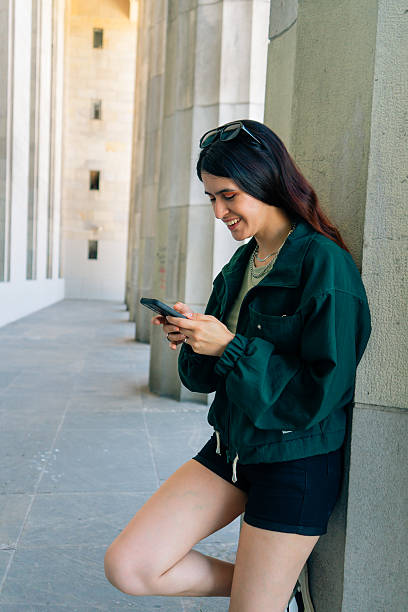 Latin tourist using smartphone in a building with columns