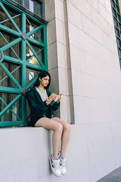 istock Young latin woman reading a book outside a building 2202331834