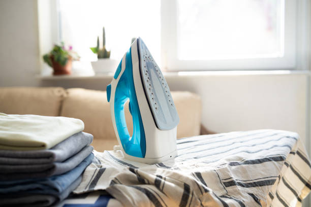 istock Electric iron and pile of clothes on ironing board 2202332268