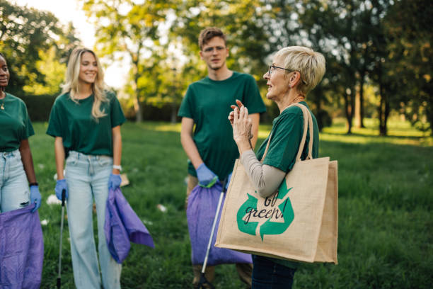 istock Group of volunteers discussing while picking up trash in park 2202333671