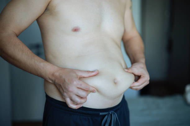 istock Overweight man checking his fat body reflection in mirror 2202339326