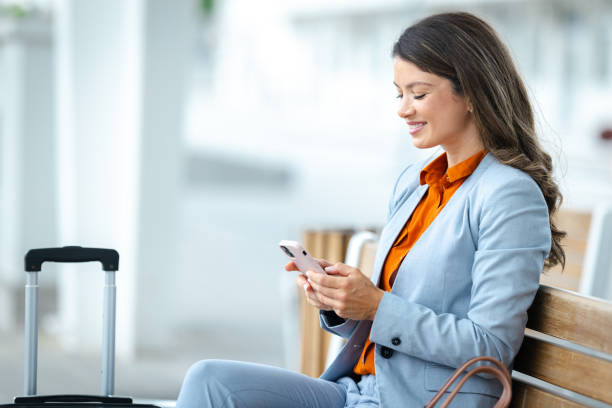 istock Professional woman sitting at train station using phone waiting for transport 2202342167