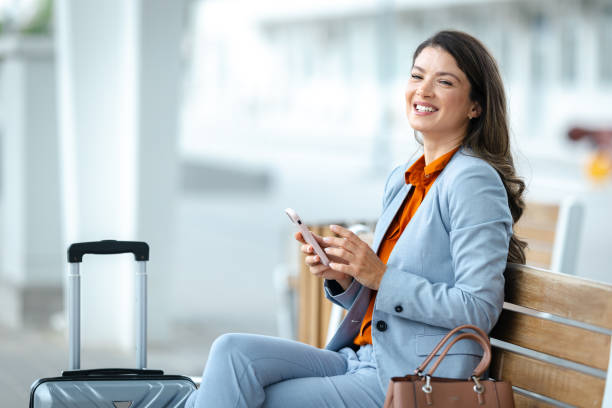 istock Businesswoman smiles while using phone at an train station 2202342746
