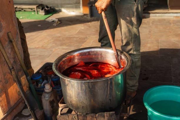 Man dyeing  fabric on street in India in vibrant red colour