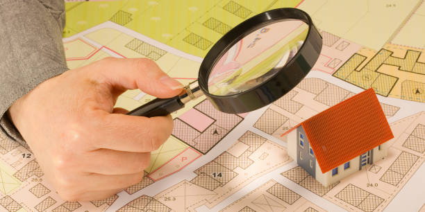 istock Searching new home - Concept with home model, magnifying glass and imaginary cadastral map 2202349896