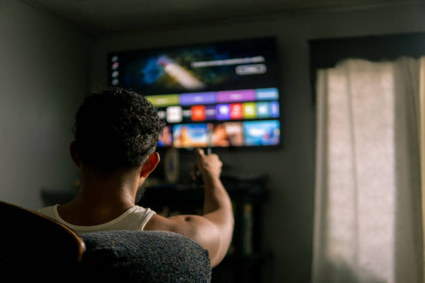 istock Man relaxing on sofa watching streaming service on television 2202357803
