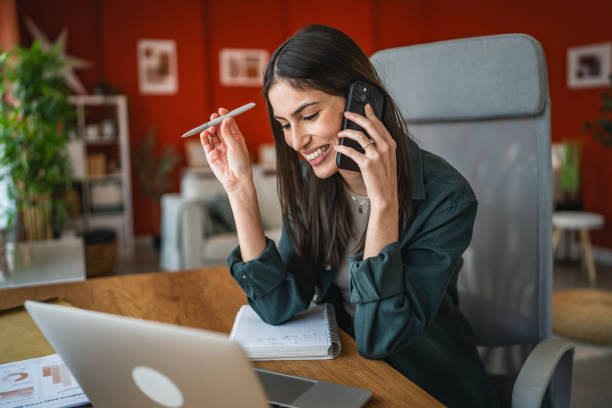 istock smiling woman work on laptop from home office while talk on mobile phone 2202361133
