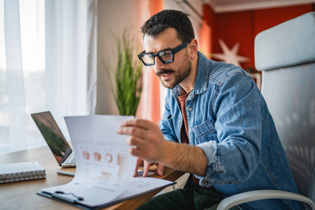 istock focused concentrated man work on clipboard and laptop at home office 2202361875