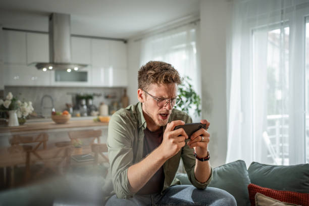 istock Young man having fun with a mobile game on his phone 2202368512
