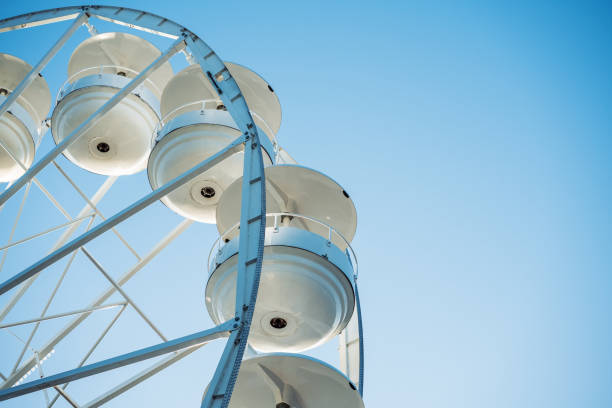 A large Ferris wheel stands prominently against a bright blue sky, reflecting sunlight and inviting visitors. Bulgaria, Pomorie