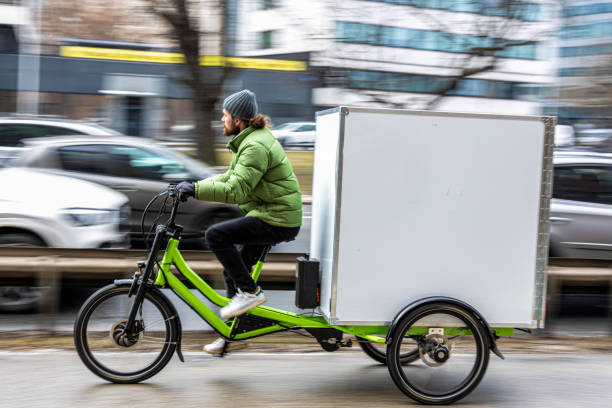 Bicycle courier delivering parcels in the city on a cargo bike