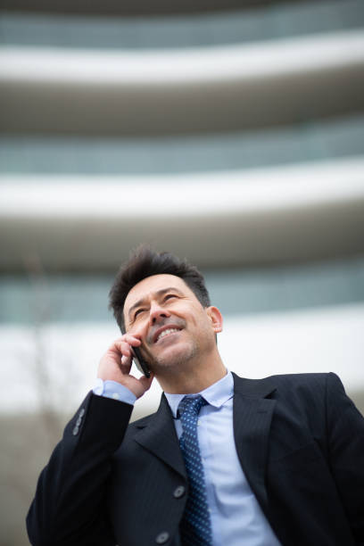 Close-up portrait of happy businessman talking on mobile phone outside a building