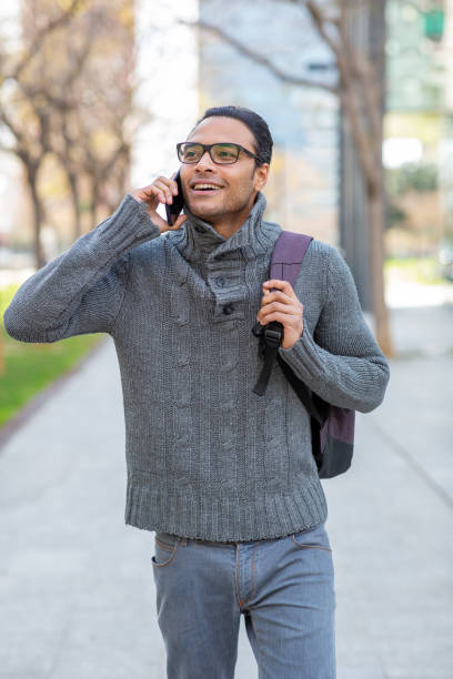 istock Handsome mixed race man talking on mobile phone with bag in the city 2202381432