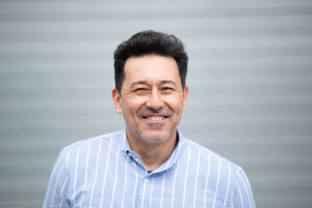 istock Smiling mature latin man standing against grey background 2202381676