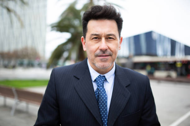 Close-up portrait of confident mature businessman standing outside staring at camera