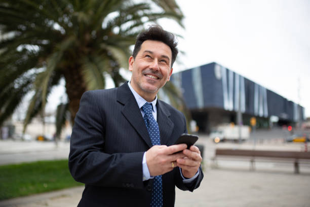 istock Happy businessman with mobile phone walking outside 2202381756