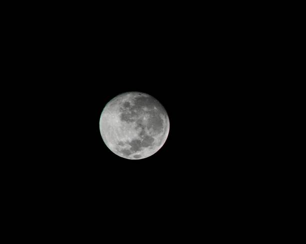 A detailed, close-up view of the full moon isolated against a dark, barren night sky, displaying its remarkable lunar surface textures and crater details.