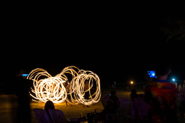 istock Artist fire juggling performance on the beach. 2202404449