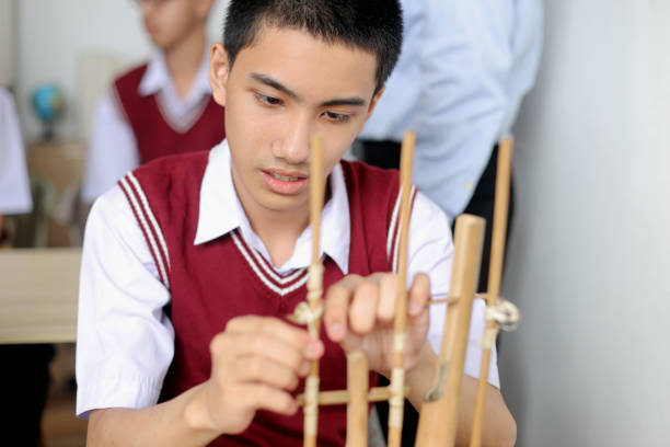 Bandung, Indonesia-April 8, 2014:  An angklung craftsman carves bamboo to form one of the traditional Indonesian instruments known as the angklung.