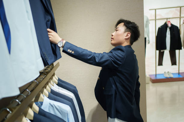 istock Man choosing clothes in men's clothing store 2202413368