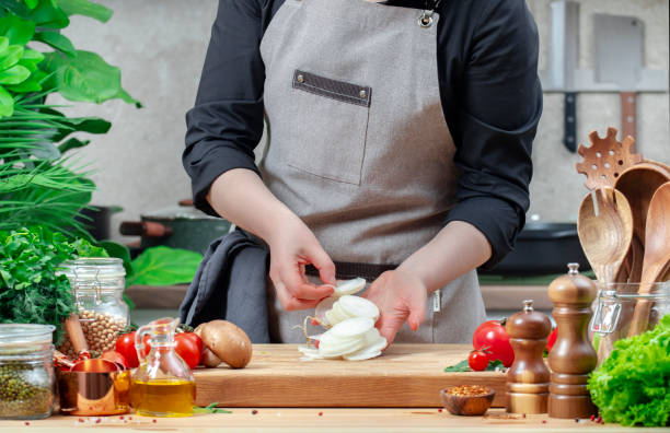 istock Chef holds slices of white radish in hands. Cozy kitchen with wooden table, kitchenware, vegetables, herbs and ingredients for cooking. Healthy vegan eating, culinary, recipes, food blogging 2202418310