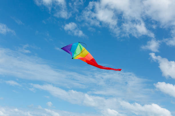 istock rainbow-colored kite flying high in the sky against a backdrop of white clouds 2202421851