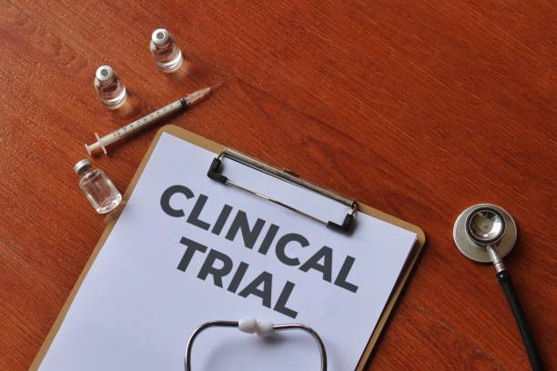 istock A clipboard with the words CLINICAL TRIAL on a wooden table. 2202422574