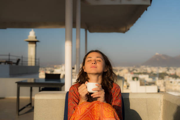 Woman drinking tea sitting in rooftop cafe during trip to India Serene woman drinking tea in the morning sitting in rooftop cafe during trip to India peaceful cafes stock pictures, royalty-free photos & images