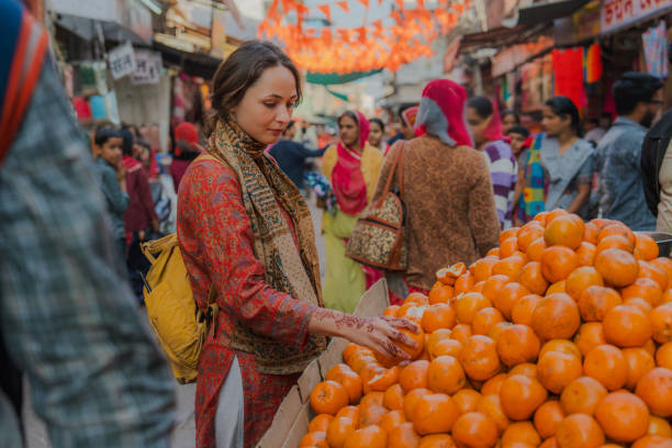 Serene woman buying oranges on busy market during her culture trip to India