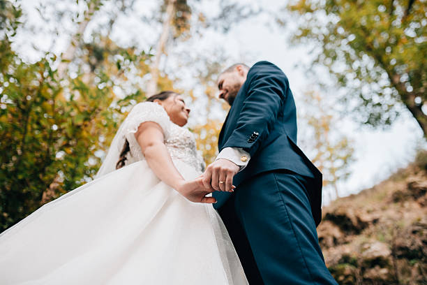 istock Low angle view of bride and groom kissing surrounded by forest. 2202430302