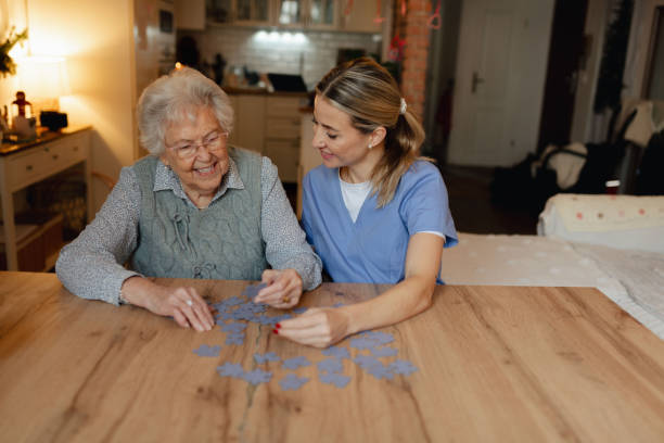 istock Friendly caregiver and elderly patient working on puzzle together, having fun. 2202430642