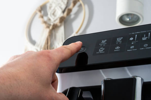 istock Close-up of a hand pressing power button on a coffee machine, modern kitchen interior 2202438817