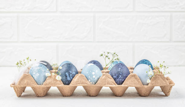 istock Cute easter eggs in a cardboard package with flowers on light background. Happy easter concept. copy space 2202439982