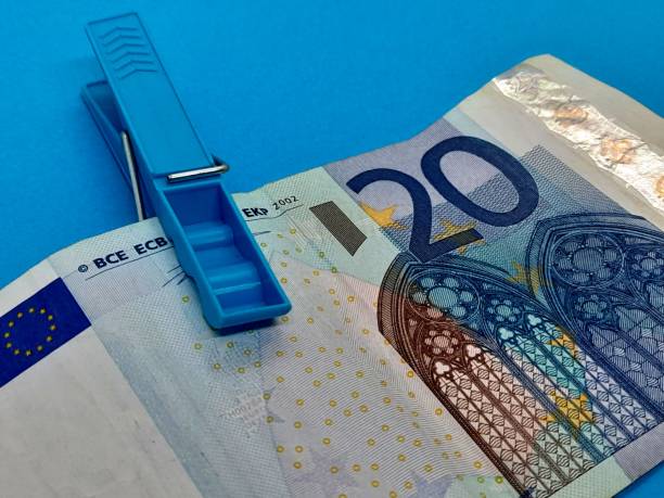 istock 20 euro banknote with blue clothespin and blue background. 2202440274