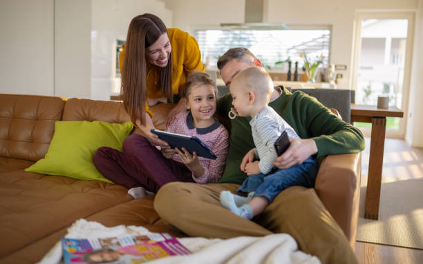 istock Young Family Sitting On Couch Absorbed In Digital Devices 2202440651
