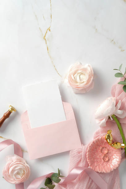 istock Flat lay composition with a pink envelope, blank card, and flowers on a marble background. Ideal for wedding invites, greeting cards, or romantic messages 2202443177