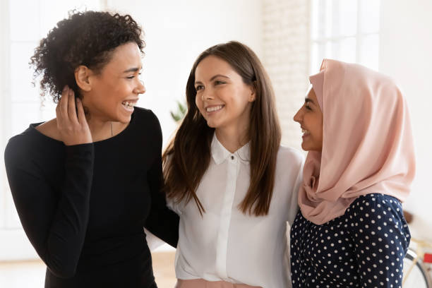 Multicultural women colleagues, students or friends hugging indoor