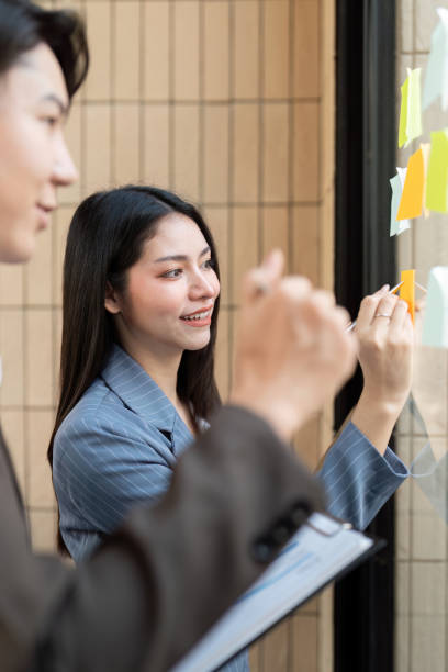 istock Team members collaborating on project ideas with sticky notes on a glass board. 2202445987
