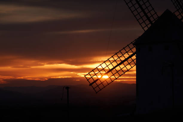 Sunset over the windmills of Campo de Criptana, casting a golden glow on the iconic landscape of Castilla-La Mancha, Spain, famously linked to Don Quixote