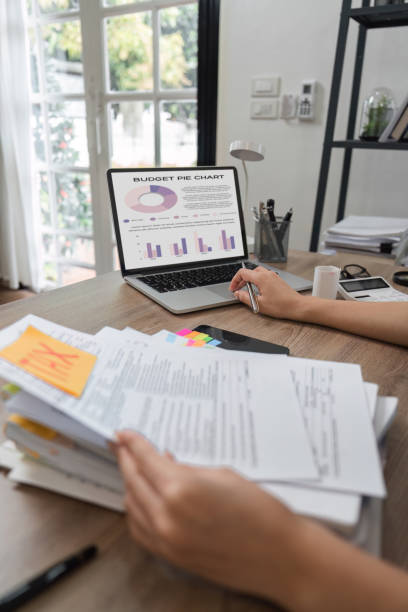 istock Accountant analyzing budget pie chart and reviewing financial documents. 2202447095