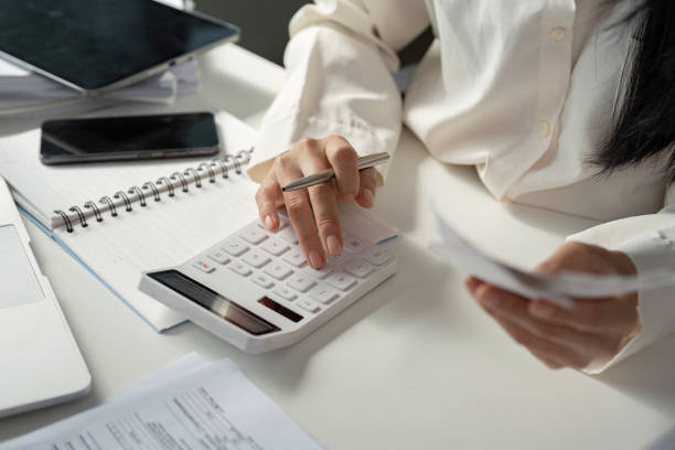istock Calculating financial data with a calculator while reviewing receipts and notes for tax preparation. 2202448275