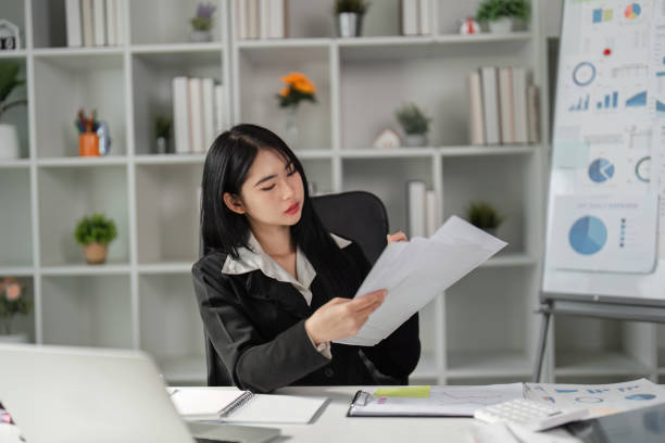 istock Focused woman examining financial documents in a contemporary office. 2202450628