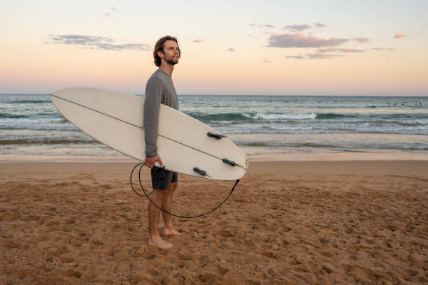 istock Surfer Standing on the Beach at Dusk 2202450986