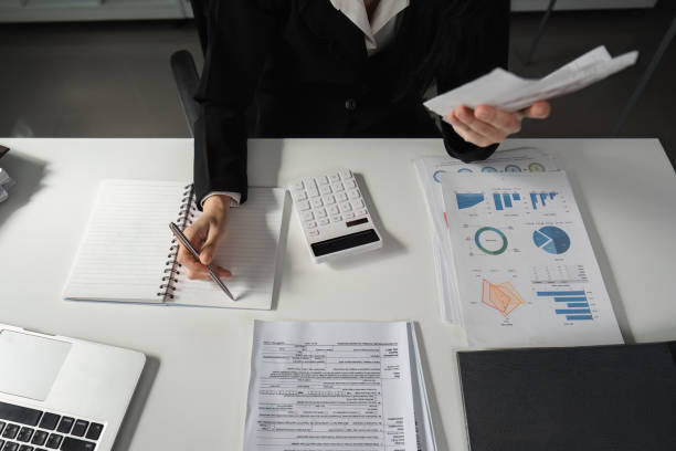 istock Accountant reviewing financial documents and taking notes with a calculator. 2202451170