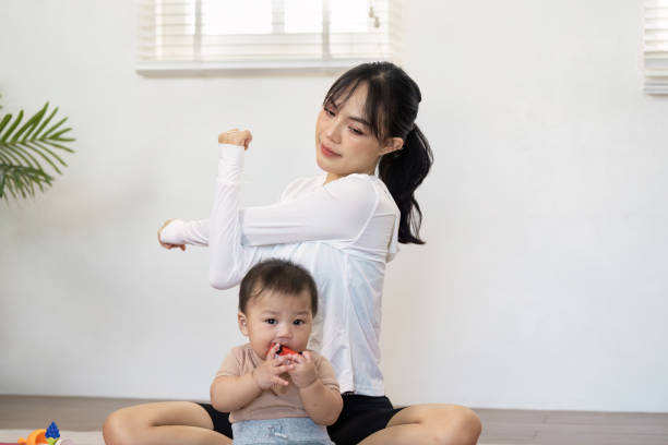 istock Asian mother exercising while playing with her baby at home, promoting wellness and active parenting 2202452828