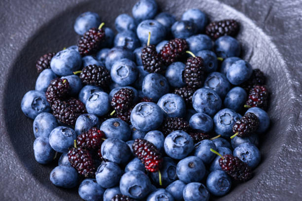 istock Dark berries assortment: blueberries, blackcurrants, and mulberries 2202454626