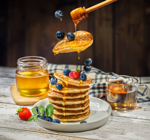 istock Pancakes and berries topped with honey, pancake levitation, 2202455569