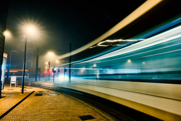 istock Lightrail train passes by at night  in curved street 2202456555
