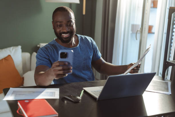 istock Man working from home using phone and laptop at modern home office 2202457939
