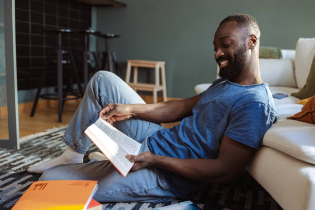 istock Man enjoys relaxing at home while reading a book in cozy atmosphere 2202458401